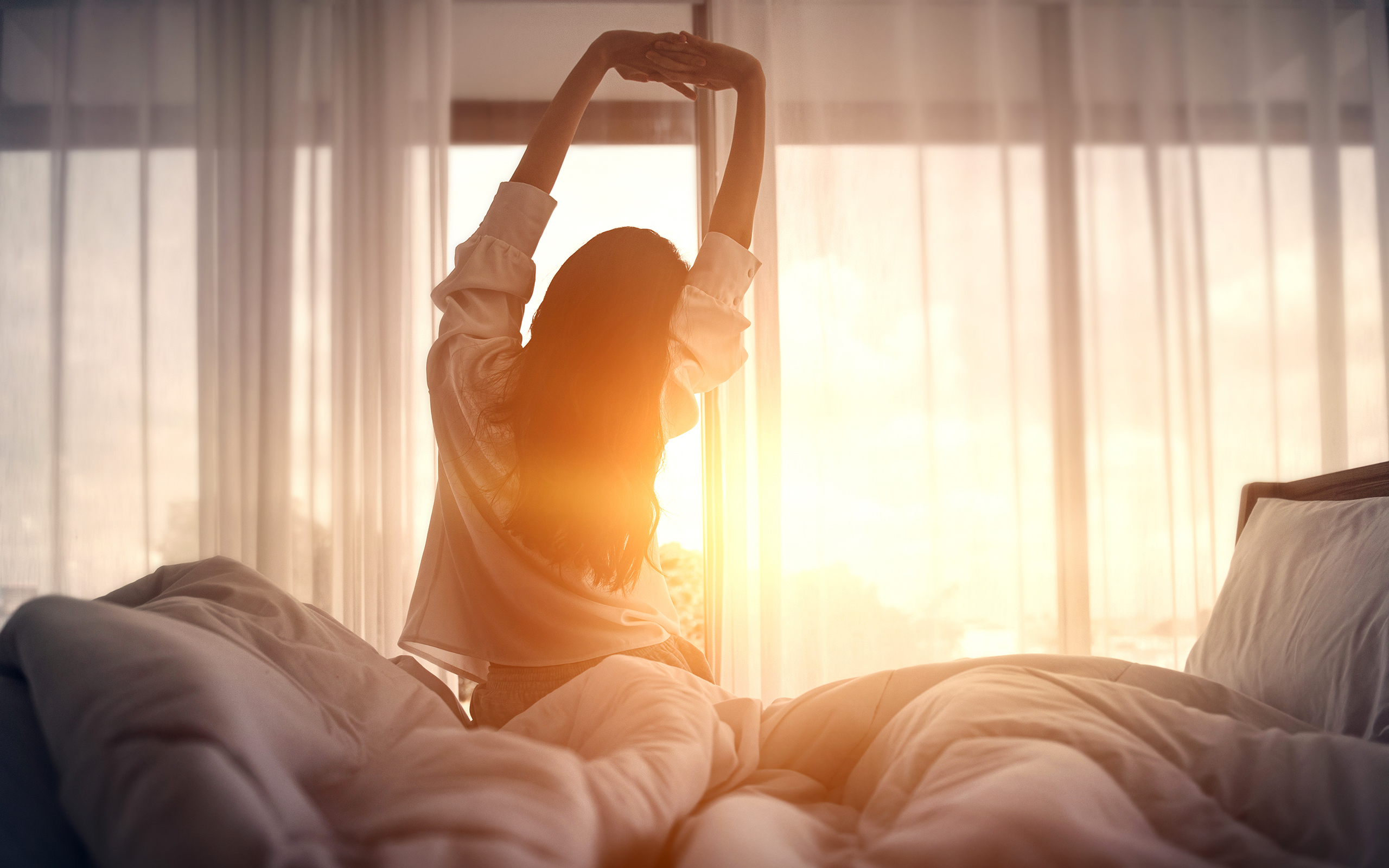 Eine Frau streckt sich entspannt am Morgen beim Aufstehen