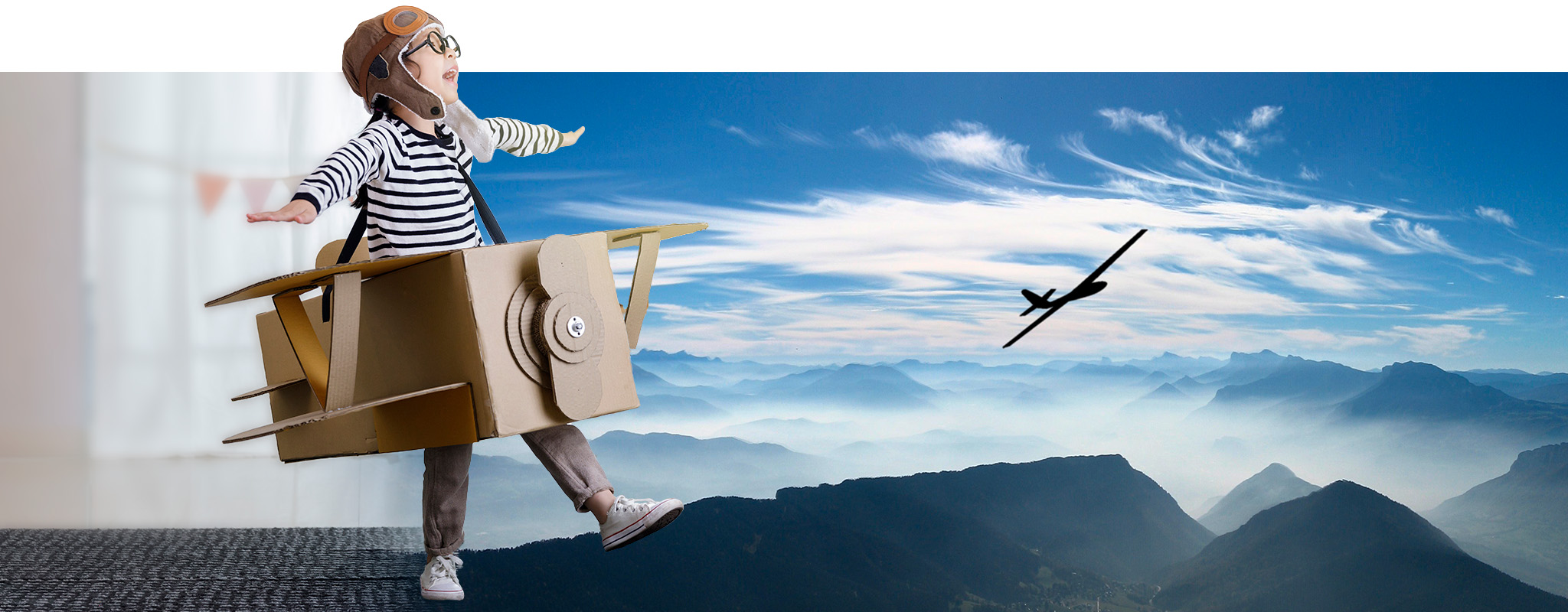 Kind spielt mit einem selbstgebauten Flugzeug, daneben Himmel mit einem echten Segelflugzeug